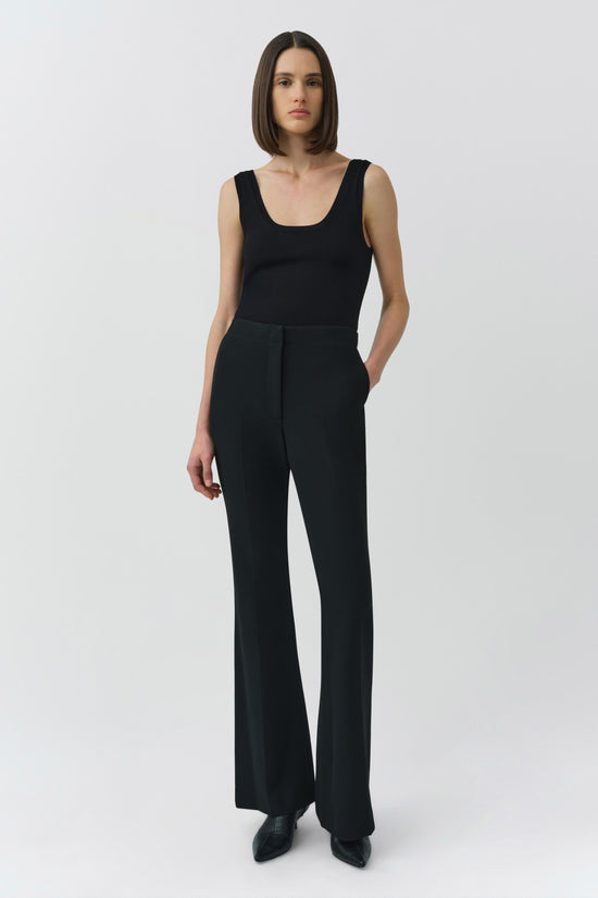 Woman wearing black sleeveless tank top with wide-leg pants and black shoes.
