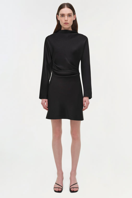 Black satin mini dress with long sleeves, wrap front detail, and A-line skirt worn with black strappy sandals.
