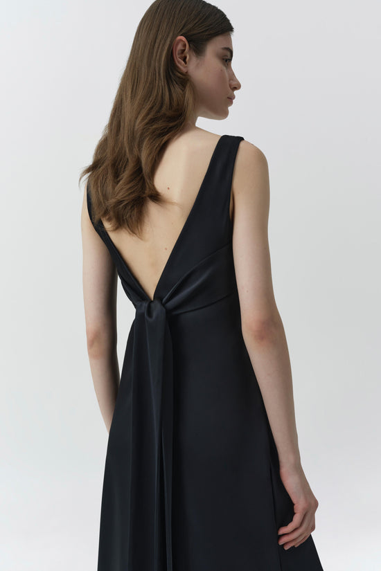 Black sleeveless gown with deep V-back and tie detail at neckline, shown from rear view.