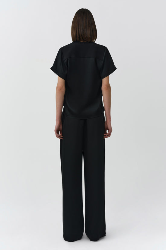 Black short-sleeved t-shirt with rolled cuffs, shown from back view on a model.