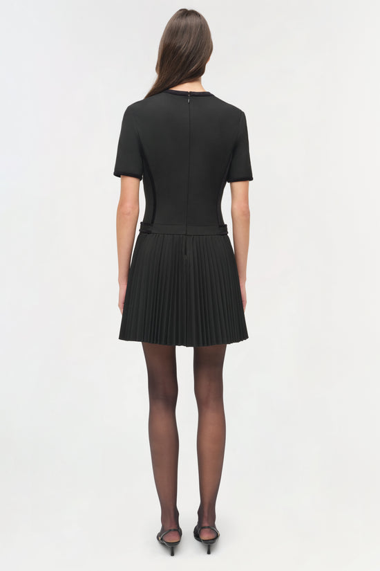 Black mini dress with short sleeves and pleated skirt, shown on model from back view.