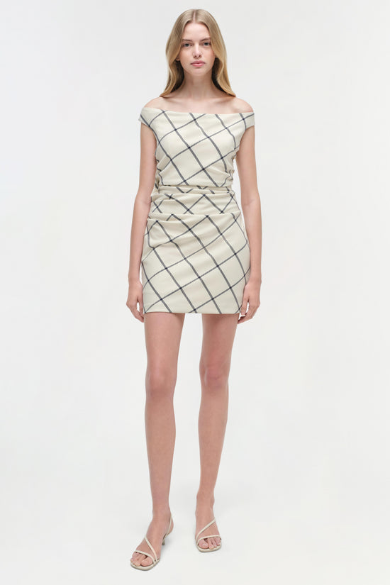Cream mini dress with diagonal grid pattern and off-shoulder neckline, styled with white sandals.