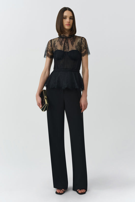 Black lace bustier top with sheer lace short sleeves and structured bodice worn with wide-leg black pants.