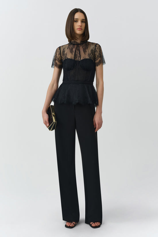 Black lace bustier top with sheer lace short sleeves and structured bodice worn with wide-leg black pants.
