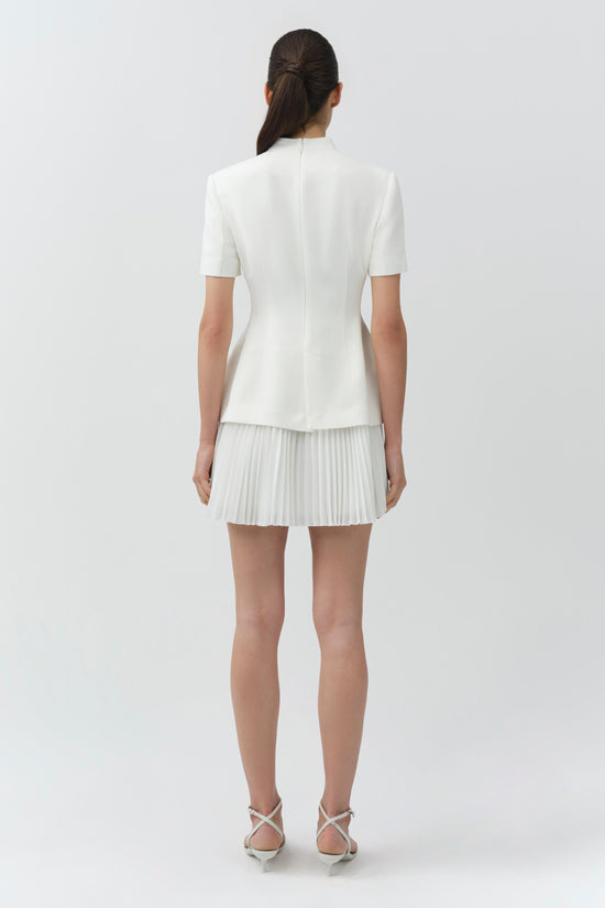 White blazer mini dress with short sleeves and pleated skirt, shown from back view on model.
