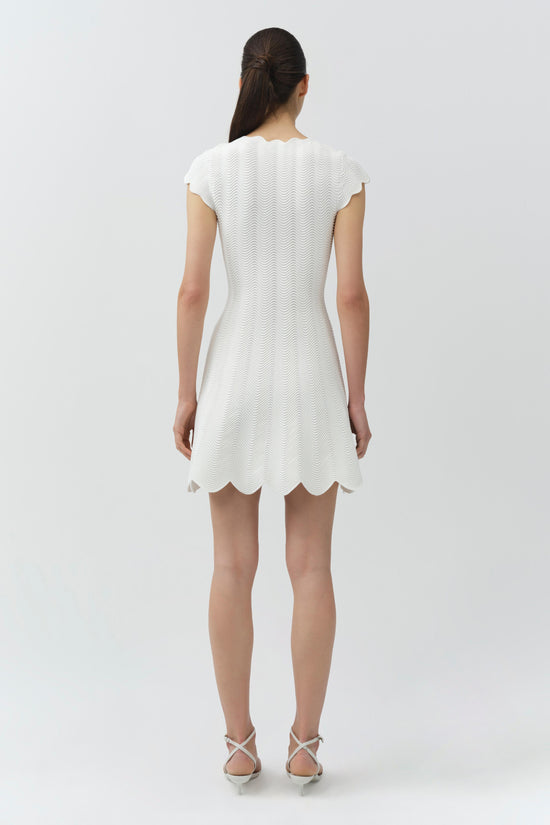 Cream wavy knit mini dress with short sleeves and scalloped hem, shown on model from back view.