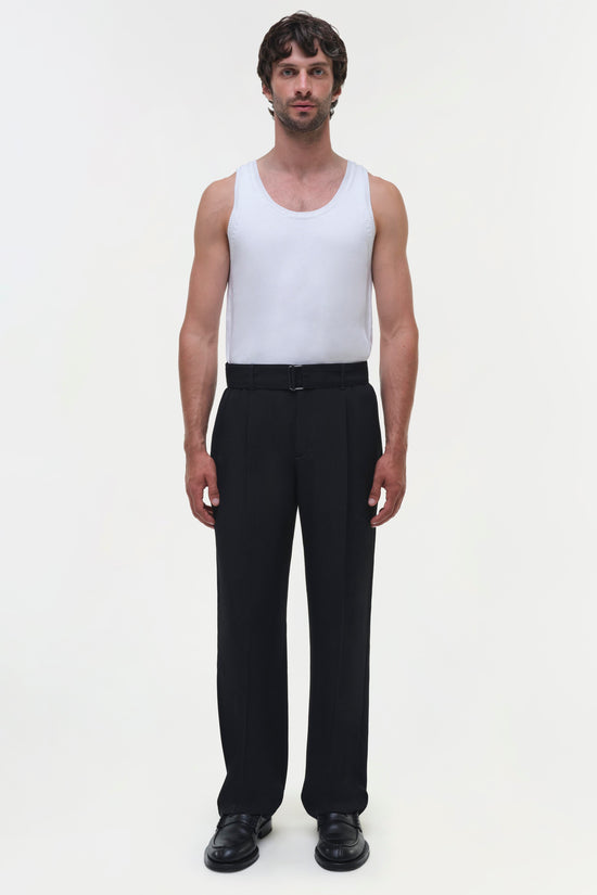 Man wearing black trousers with pleated front and belt, paired with white tank top.
