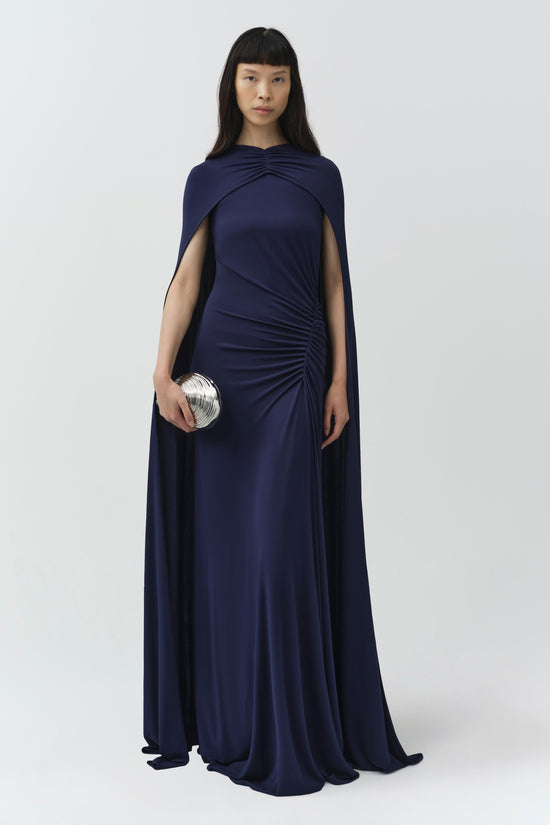 Navy draped jersey gown with detached cape overlay and ruched side detail.