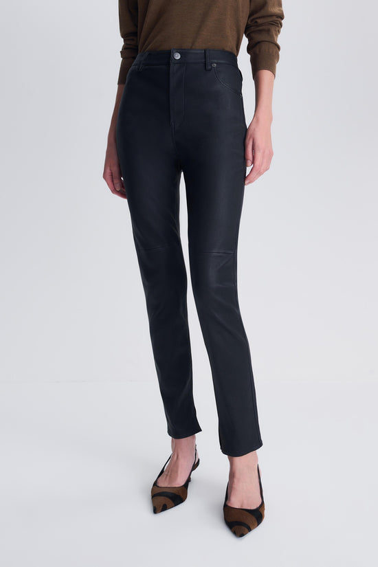 Black leather high-rise skinny pants with straight leg, shown with brown sweater and leopard-print mules.