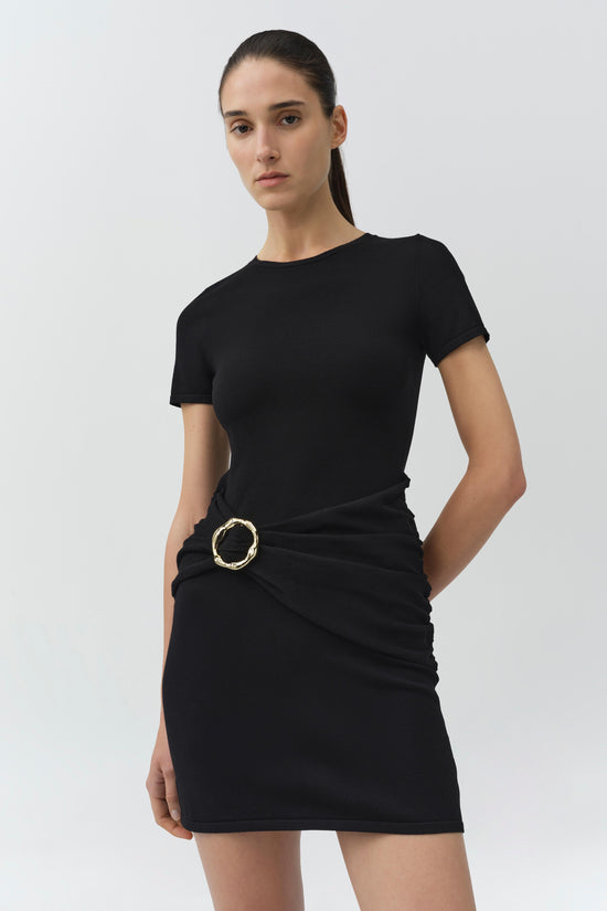 Black knit mini dress with short sleeves, crew neckline, and draped waist detail with gold circular buckle.