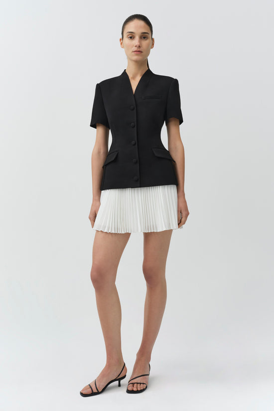 Black short-sleeve blazer with white pleated mini skirt bottom, button front closure, and chest pockets.