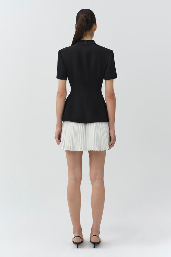 Black short-sleeve blazer dress with white pleated skirt, shown from back view.