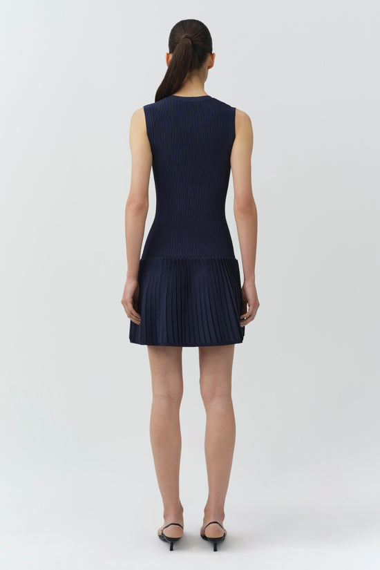 Navy ribbed knit sleeveless mini dress with pleated skirt hem, shown from back on model.