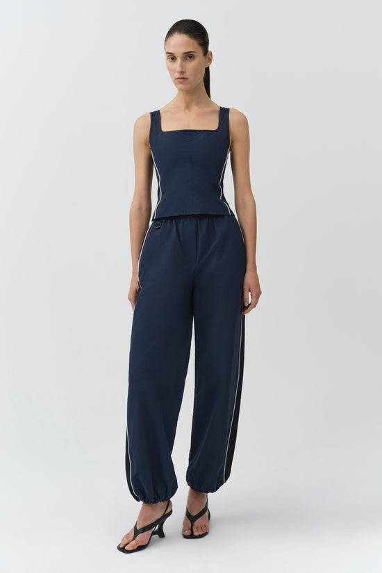 Woman wearing navy cotton faille jogger with white stripe detailing and matching sleeveless square-neck top.