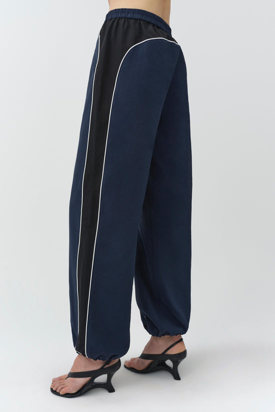 Navy and black cotton faille joggers with white piping detail and elasticized ankles.