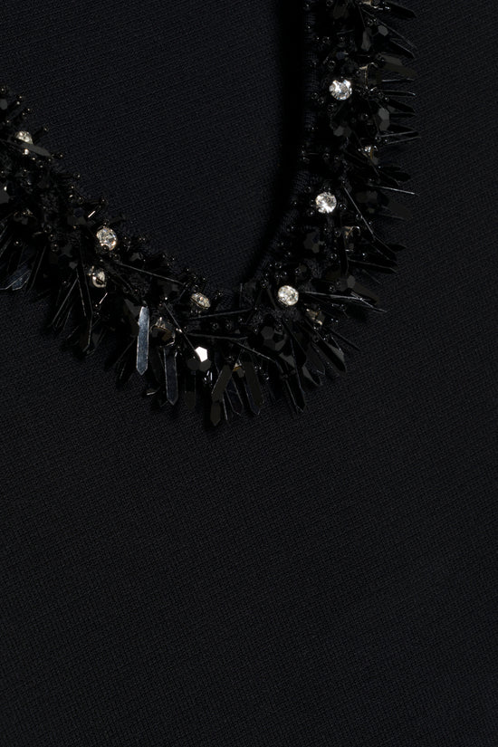Black knit mini dress with jeweled and spiked neckline detail.
