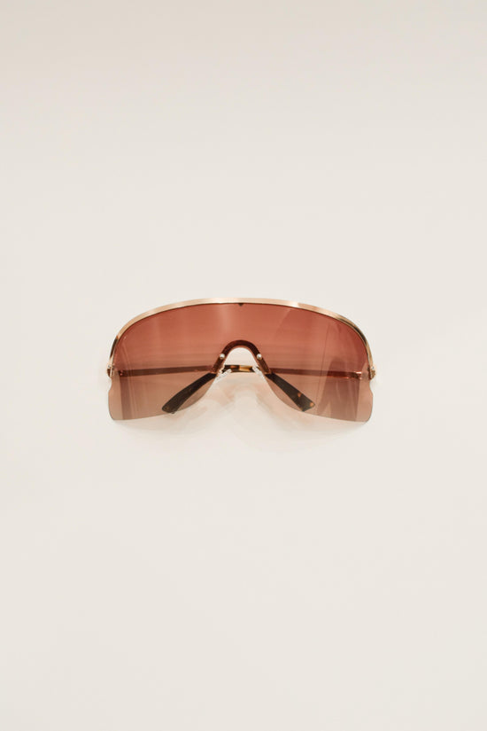 Oversized shield sunglasses with rose-tinted lenses, thin metal bridge, and tortoiseshell-patterned arms on neutral backgroun