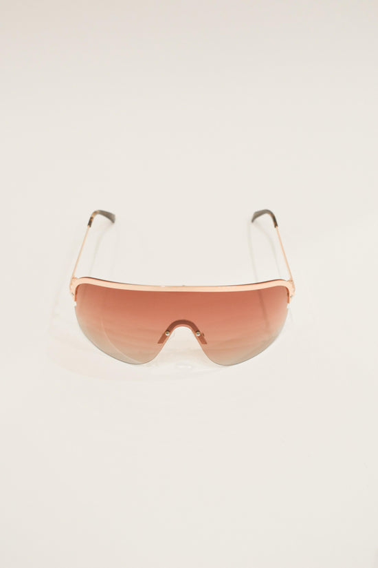 Oversized shield sunglasses with gradient peach-to-clear lenses and rose gold metal frames with white arms.