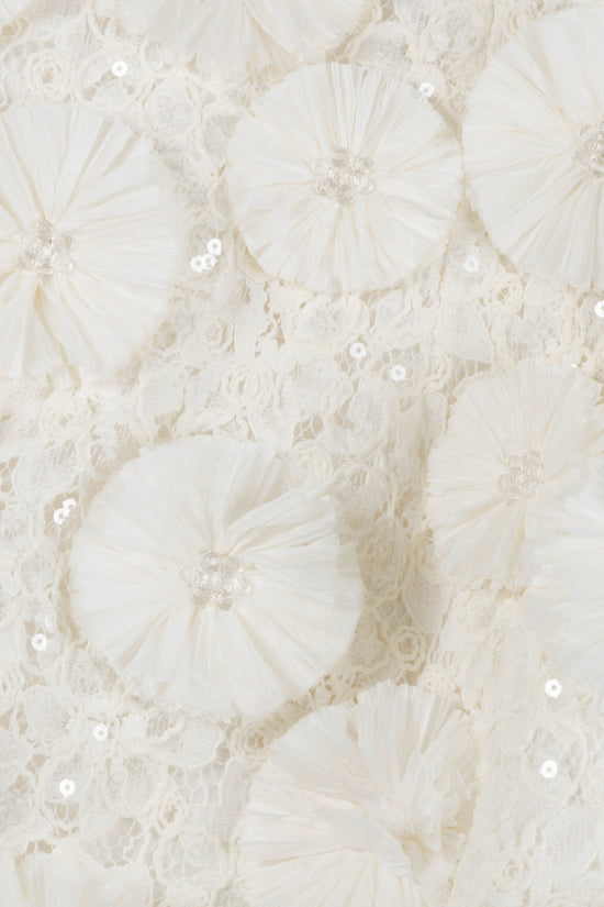 Cream-colored fabric with pleated floral appliqués, lace detailing, and scattered sequins.