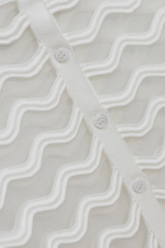 Cream knit cardigan with wavy texture pattern and white four-hole buttons down the front.