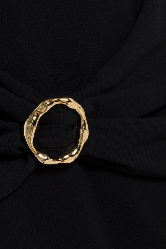 Gold-toned organic shaped ring displayed on draped black knit fabric.