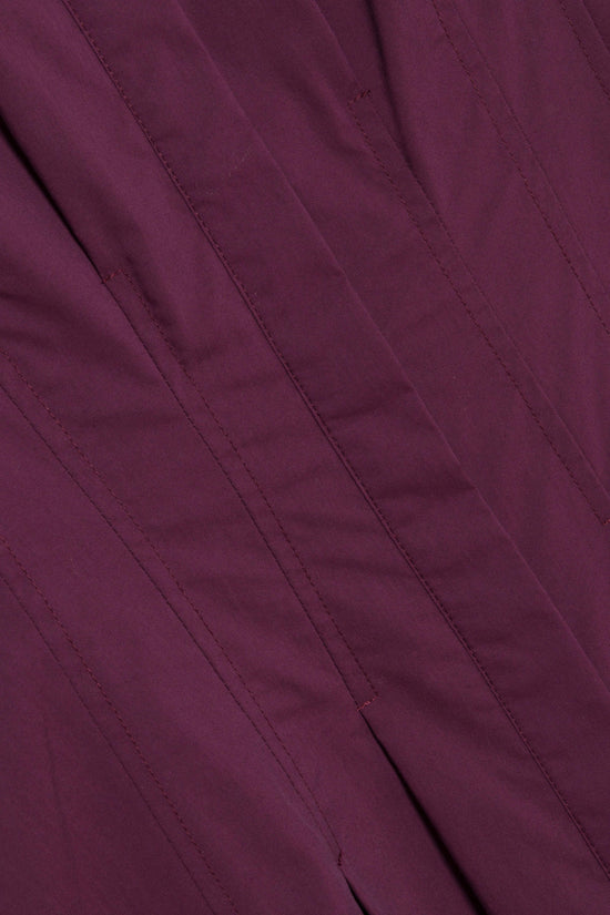 Deep purple midi dress with vertical seam detailing and draped fabric folds.