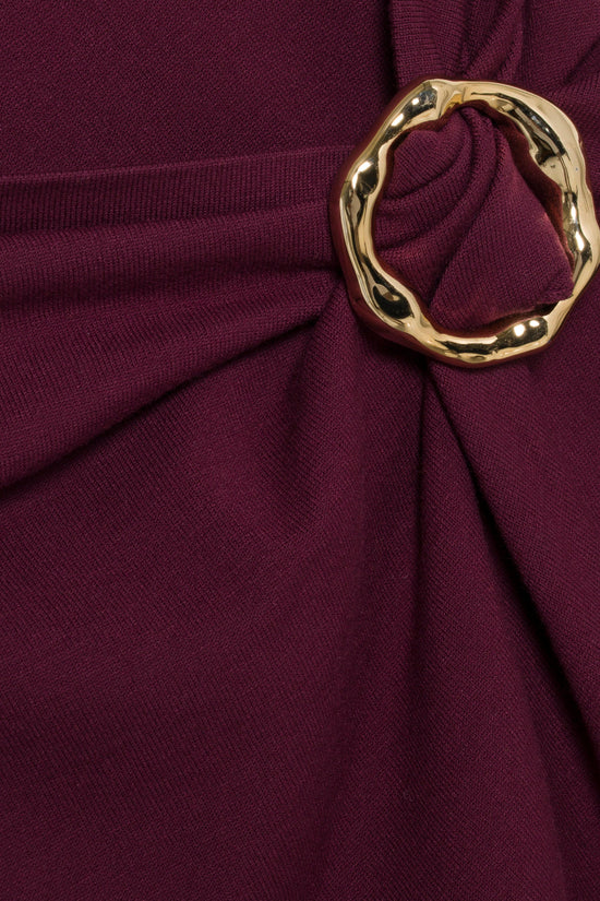 Burgundy knit midi dress with draped fabric and gold-toned decorative ring detail at waist.
