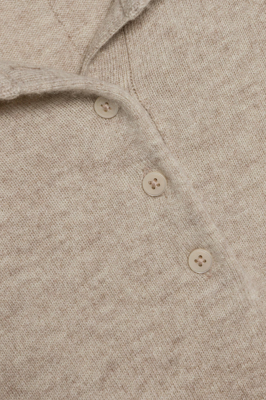 Beige cashmere polo with four-hole buttons in cream, showing textured knit fabric and collar detail.