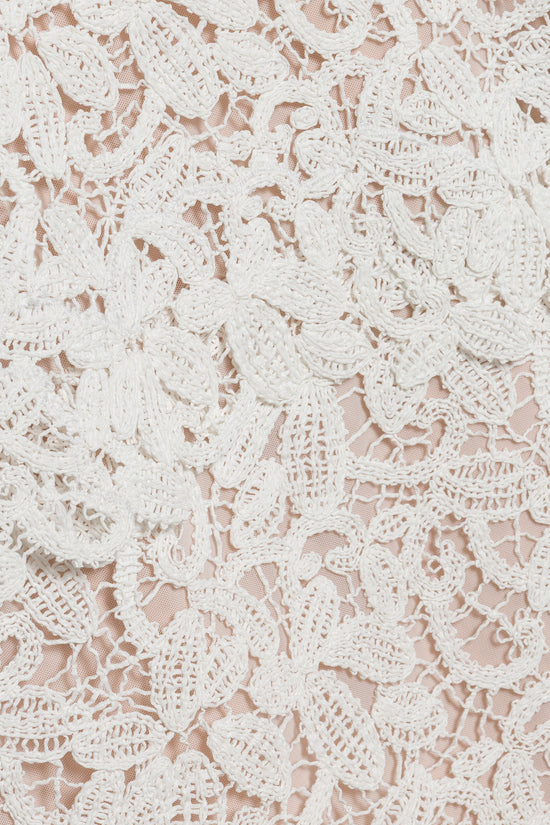 White and beige crochet lace fabric with intricate floral leaf patterns and open-weave details.