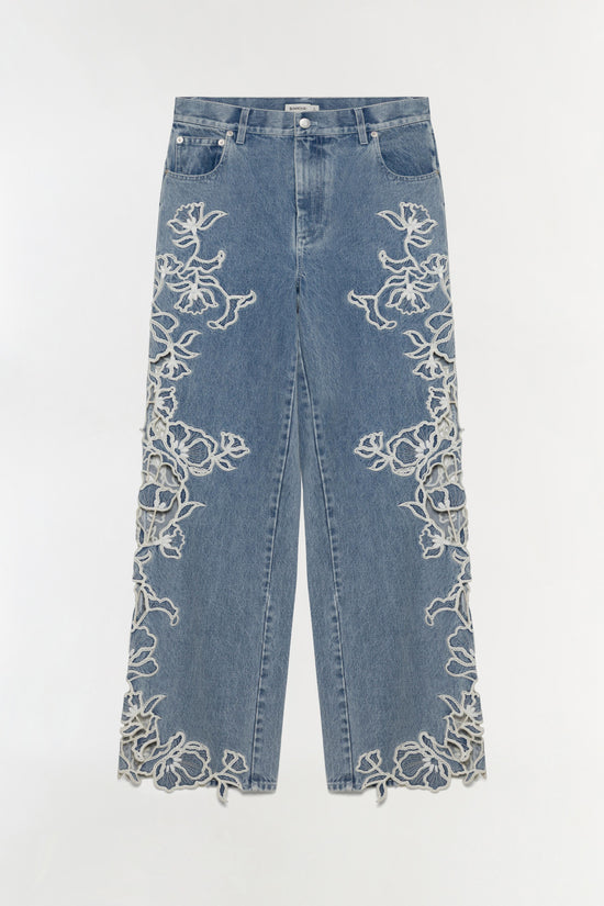 Blue denim jeans with white floral embroidery running down both outer seams and along the hem.