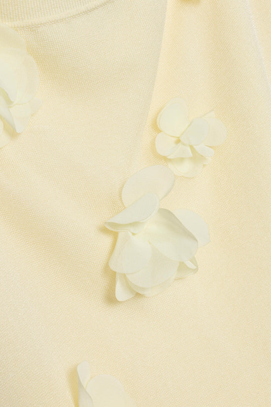 Cream knit fabric with white floral petal appliqués scattered across the surface.