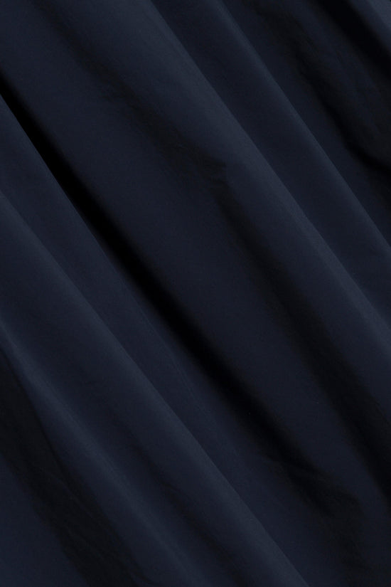 Navy cotton midi skirt with soft diagonal folds and draping throughout the fabric.