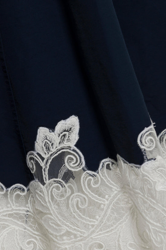 Navy cotton faille midi dress with ornate white lace trim featuring scrolled leaf motifs at the hem.