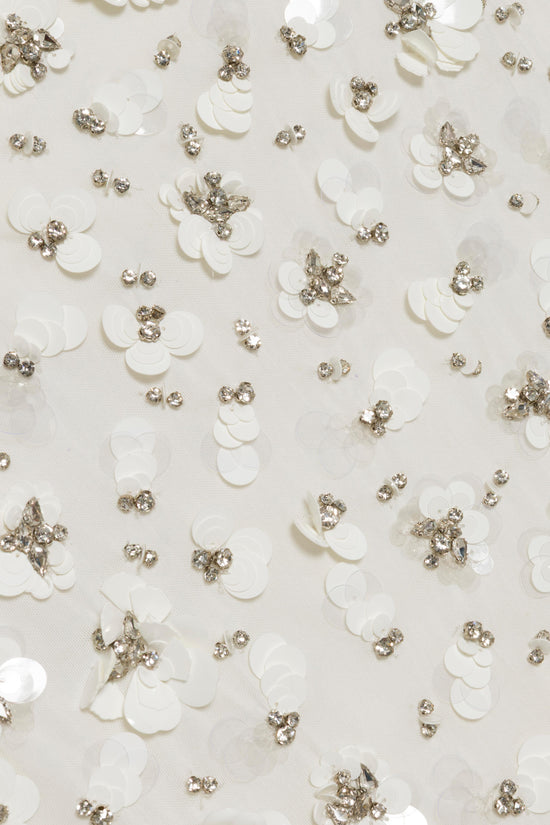 White fabric with white petal appliqués and scattered champagne-colored rhinestone clusters.