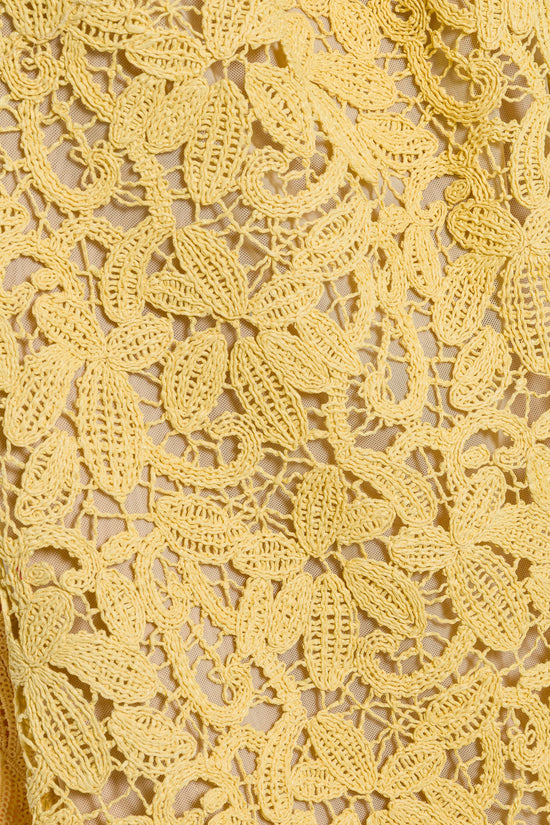 Yellow lace fabric with raised floral and leaf-shaped embroidered details on a mesh base.