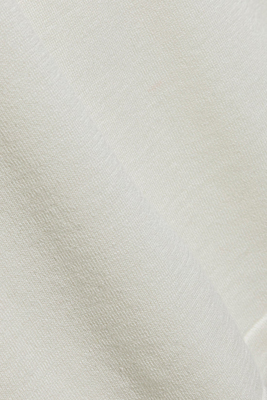 Close-up of cream-colored fabric with a textured weave pattern showing the material's surface detail.