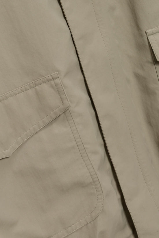 Beige jacket with quilted panels, visible front pocket, and vertical stitching details.