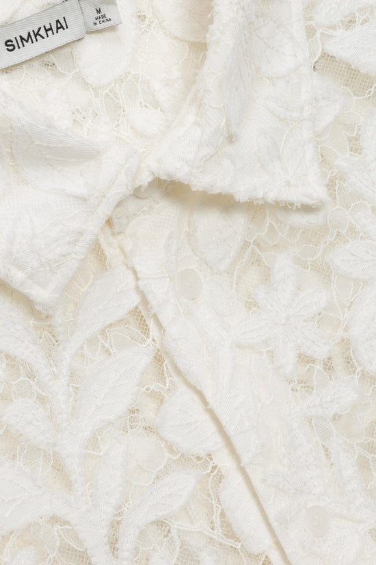 Cream lace fabric with floral pattern detail and brand label visible in corner.