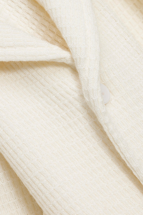 Cream-colored waffle-knit fabric with textured quilted pattern and diagonal folds.