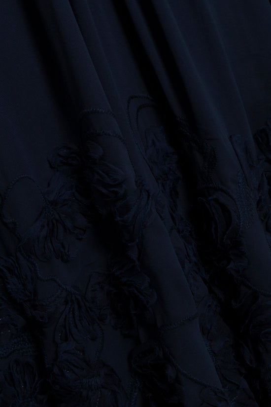 Navy mini dress with embroidered floral detailing on the hem and draped fabric folds.
