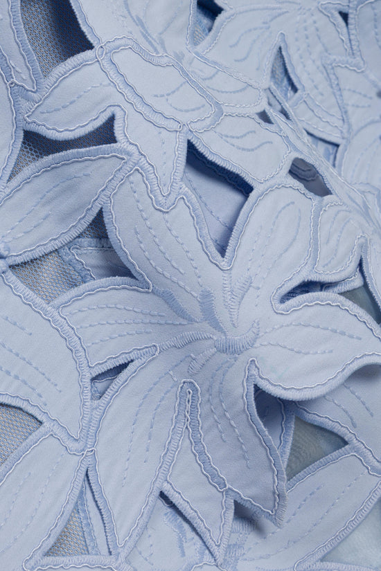 Light blue cotton fabric with leaf-shaped embroidered cutouts and visible mesh underlayer.