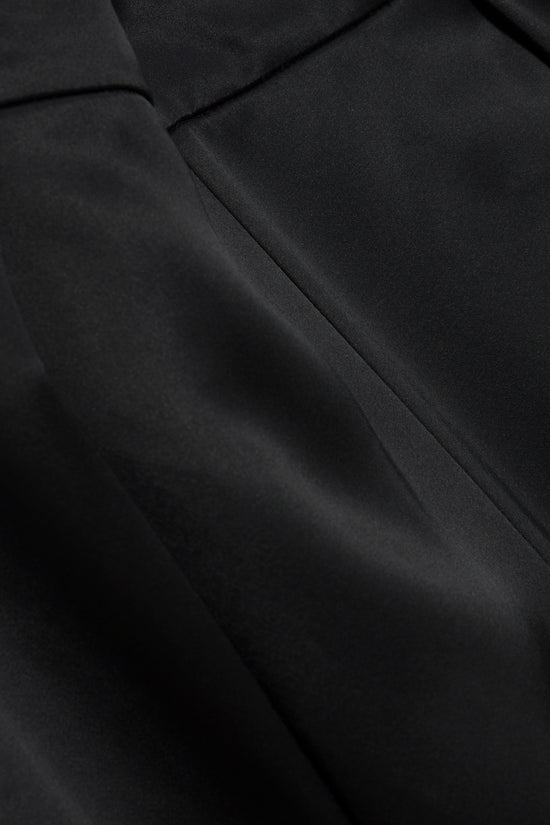 Black satin pant with a side slit, showing fabric drape and seaming details.