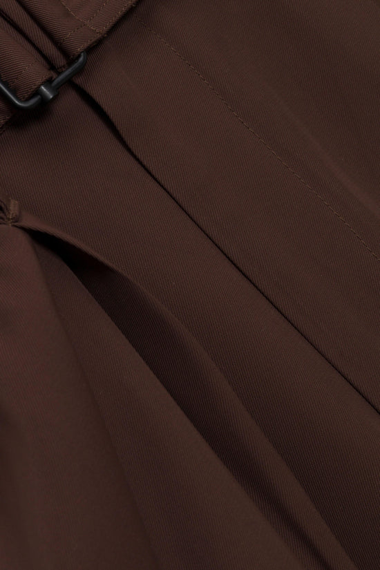 Brown ribbed trousers with black hook closure and diagonal seam detailing.