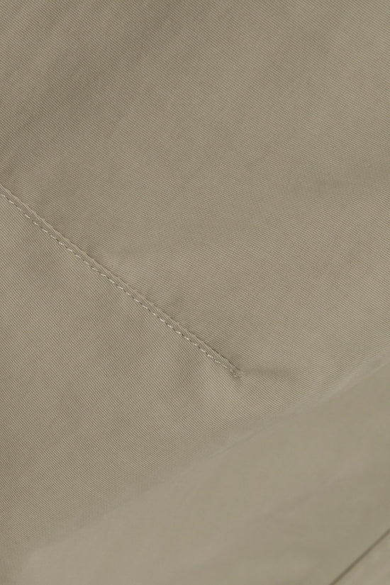 Beige technical fabric with diagonal seam detail and textured weave.
