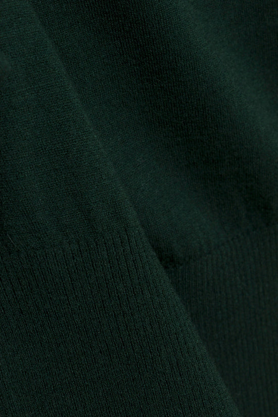 Dark green ribbed knit sweater with off-shoulder neckline and draped fabric detail.