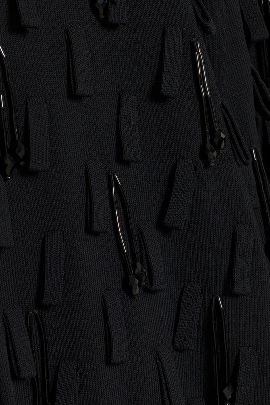 Black knit top with textured surface and black beaded embellishments scattered throughout.