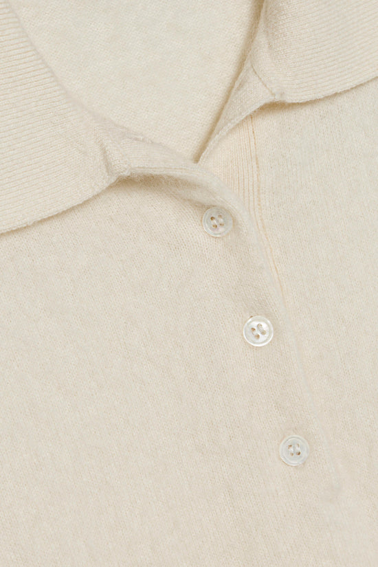 Cream brushed knit polo shirt with white buttons and ribbed texture detail.