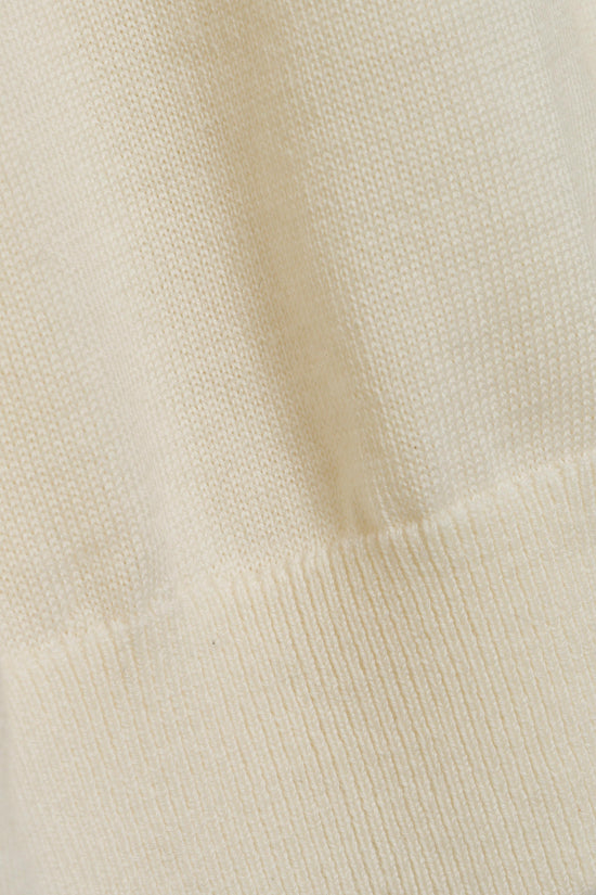 Cream-colored knit turtleneck with textured wool fabric and ribbed collar detail.
