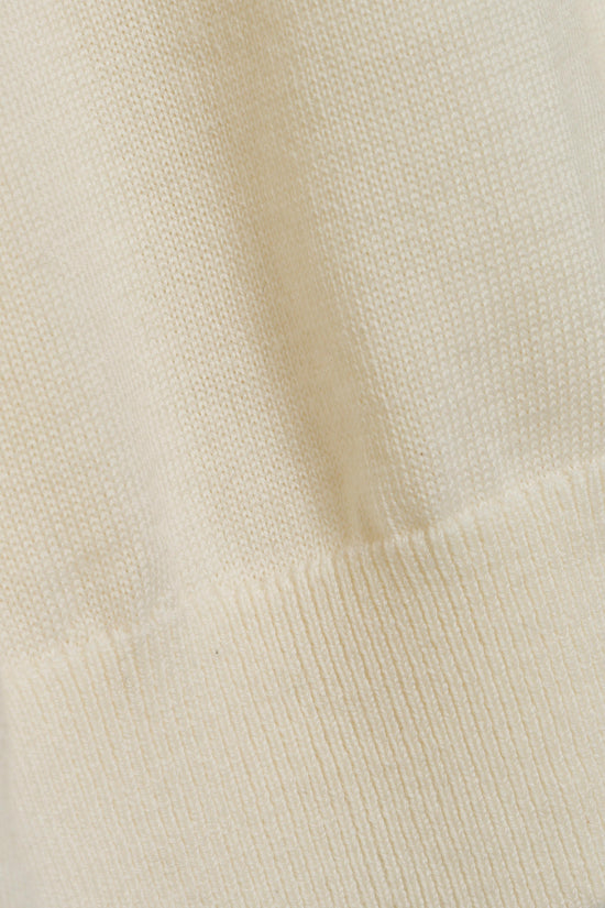 Cream-colored knit turtleneck with textured wool fabric and ribbed collar detail.