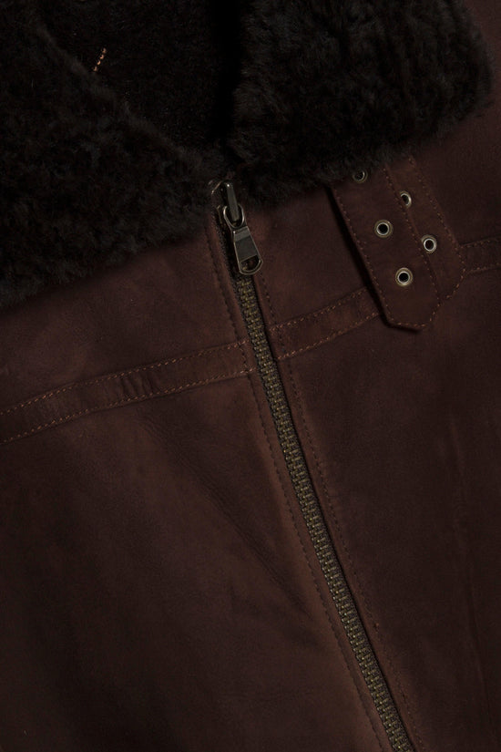 Brown shearling jacket with black fuzzy collar, metal zipper, and silver grommet details on the front panel.